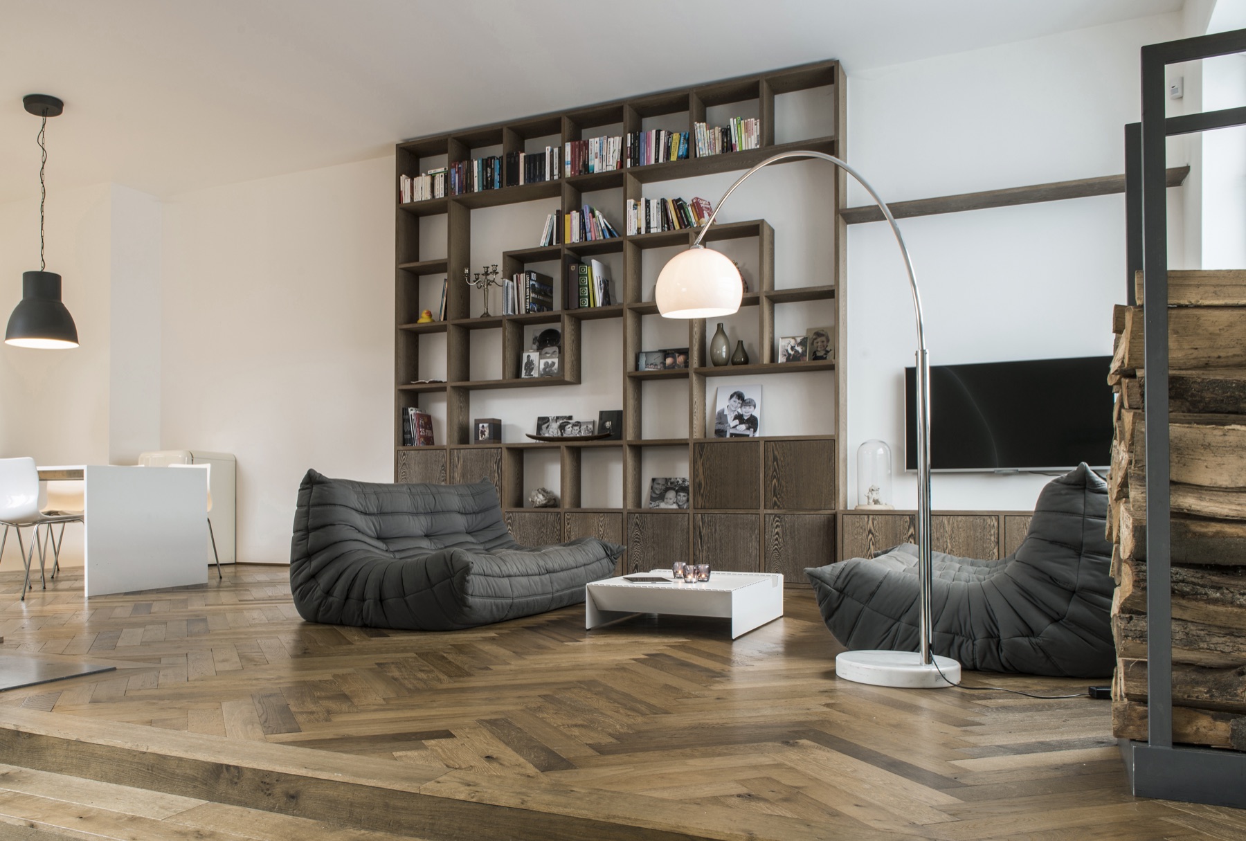 Woonkamer met warme houten visgraatvloer, zithoek en boekenkast